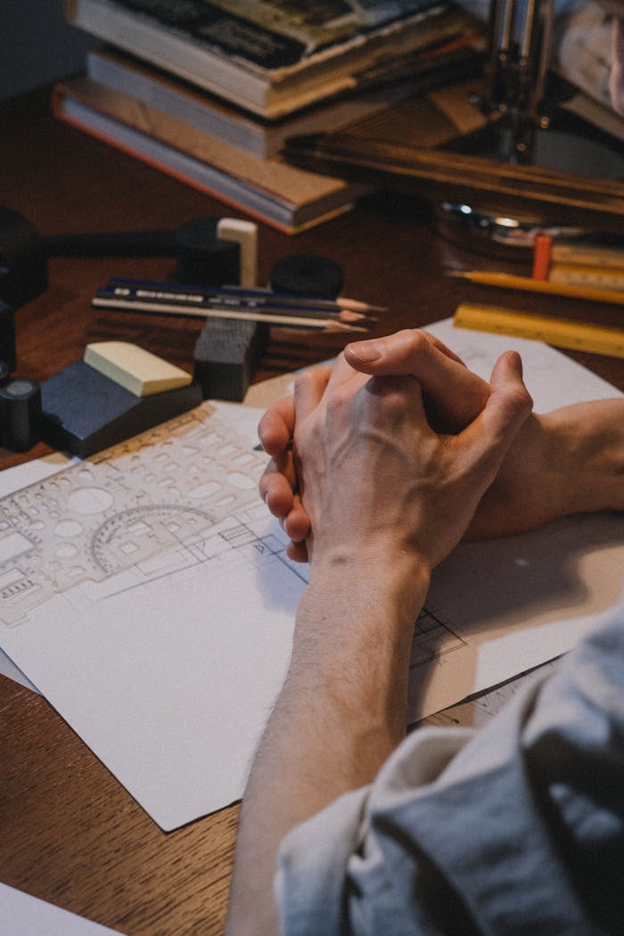 Close-up of architect's hands over a design sketch on desk, capturing creative process.